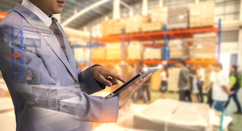 A manager using his tablet to complete inventory in a warehouse