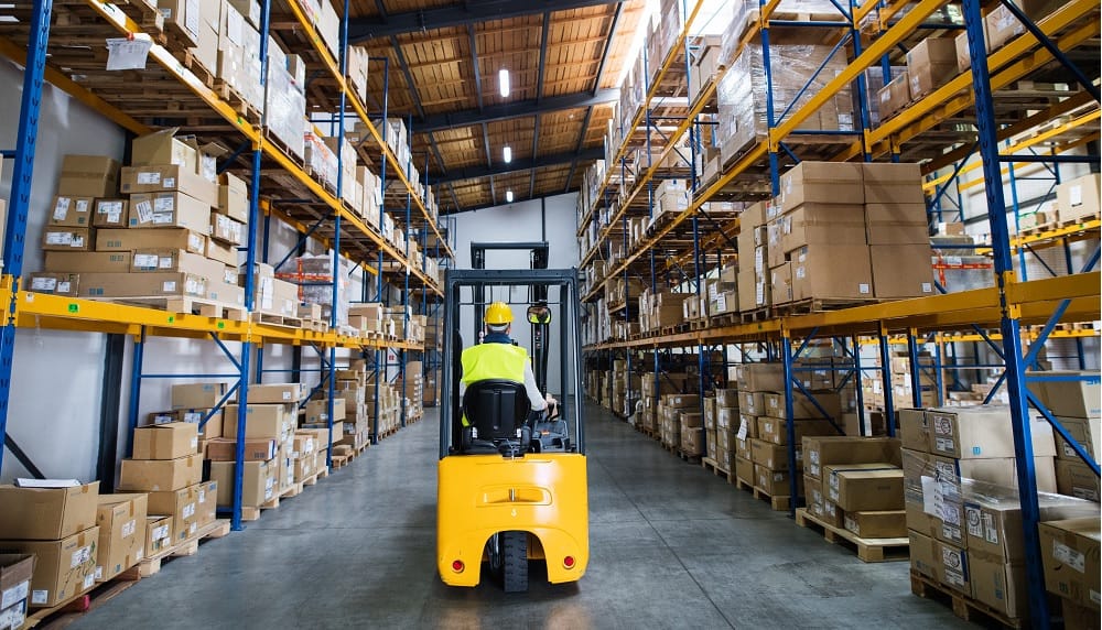 A forklift going down an aisle in a warehouse