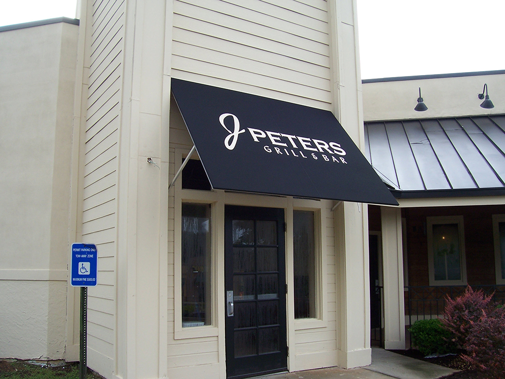A bold, custom-fabricated awning adds instant style and visibility to this restaurant entrance—designed to enhance branding and protect customers rain or shine.
