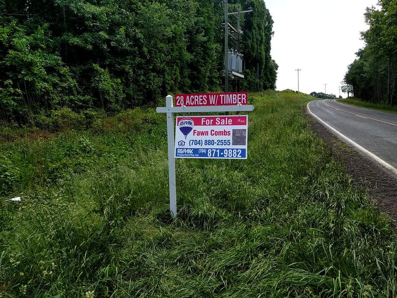 A lone real estate sign on the side of a road